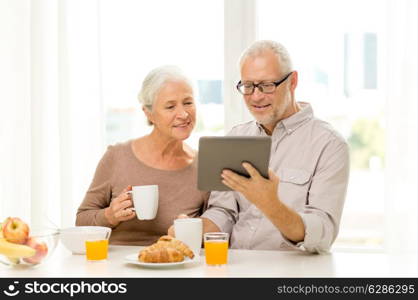 family, technology, food, drinks and people concept - happy senior couple with tablet pc computer having breakfast at home