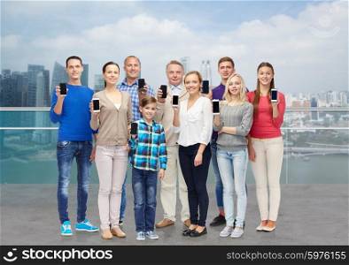 family, technology, generation and people concept - group of smiling men, women and boy with smartphones over singapore city waterside background