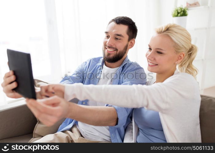 family, technology, internet and people concept - smiling happy couple with tablet pc computer at home. smiling happy couple with tablet pc at home