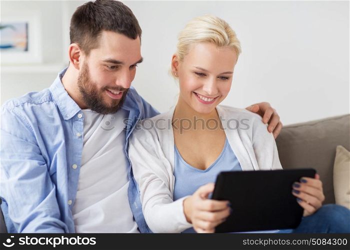family, technology, internet and people concept - smiling happy couple with tablet pc computer at home. smiling happy couple with tablet pc at home. smiling happy couple with tablet pc at home