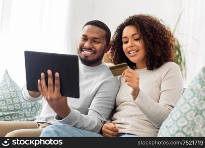 family, technology, online shopping and people concept - happy african american couple couple with tablet pc computer and credit card at home. couple with tablet pc and credit card at home