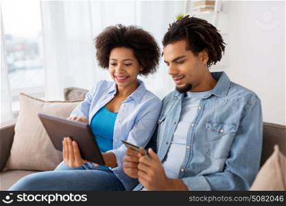 family, technology, online shopping and people concept - smiling happy couple couple with tablet pc computer and credit card at home. couple with tablet pc and credit card at home