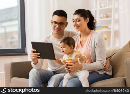 family, technology, parenthood and people concept - happy mother and father showing tablet pc computer to baby daughter at home. mother, father and baby with tablet pc at home