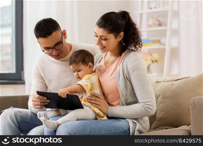 family, technology, parenthood and people concept - happy mother and father showing tablet pc computer to baby daughter at home. mother, father and baby with tablet pc at home