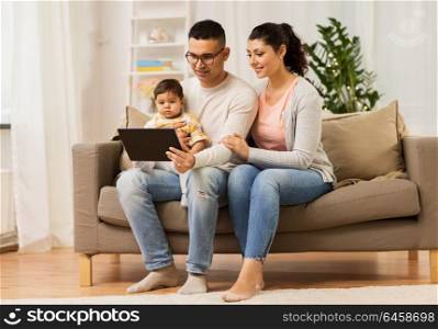 family, technology, parenthood and people concept - happy mother and father showing tablet pc computer to baby daughter at home. mother, father and baby with tablet pc at home