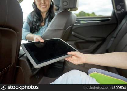 family, technology, road trip, travel and people concept - happy woman giving tablet pc computer to her child in car