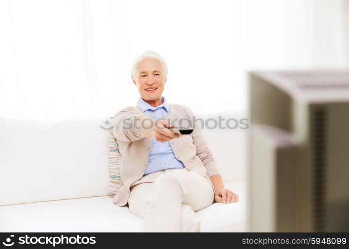 family, technology, television, age and people concept - happy senior woman watching tv at home