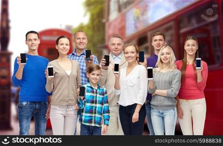 family, technology, travel and tourism concept - group of smiling people with smartphones over london city street background
