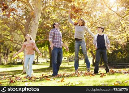 Family Throwing Autumn Leaves In The Air