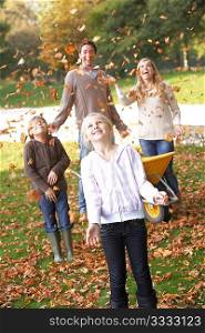 Family throwing autumn leaves into the air in garden