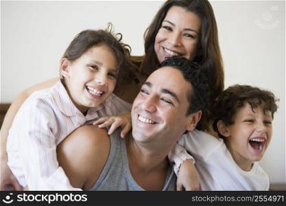 Family together on bed in bedroom smiling (selective focus)