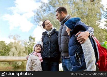 family, tourism and hiking concept - happy mother, father, son and daughter with backpacks in woods. happy family with backpacks hiking