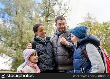 family, tourism and hiking concept - happy mother, father, son and daughter with backpacks in woods. happy family with backpacks hiking. happy family with backpacks hiking