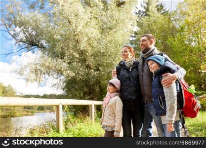 family, tourism and hiking concept - happy mother, father, son and daughter with backpacks in woods. happy family with backpacks hiking. happy family with backpacks hiking