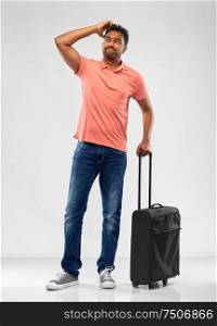 family, tourism and vacation concept - puzzled indian man in polo shirt with travel bag over grey background. puzzled indian man with travel bag shrugging