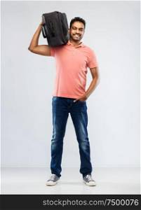 family, tourism and vacation concept - smiling indian man in polo shirt holding travel bag on shoulder over grey background. smiling indian man with travel bag on shouder