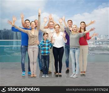 family, tourism, travel and people concept - group of smiling men, women and boy waving hands over singapore city waterside background
