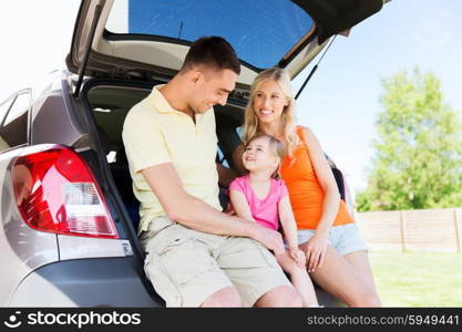 family , transport, leisure, road trip and people concept - happy man, woman and little girl sitting on trunk of hatchback car and talking outdoors