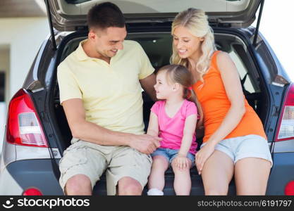 family , transport, leisure, road trip and people concept - happy man, woman and little girl sitting on trunk of hatchback car and talking outdoors