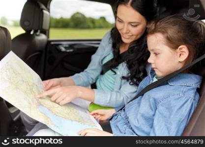 family, transport, road trip and people concept - happy woman and little daughter with map driving in car