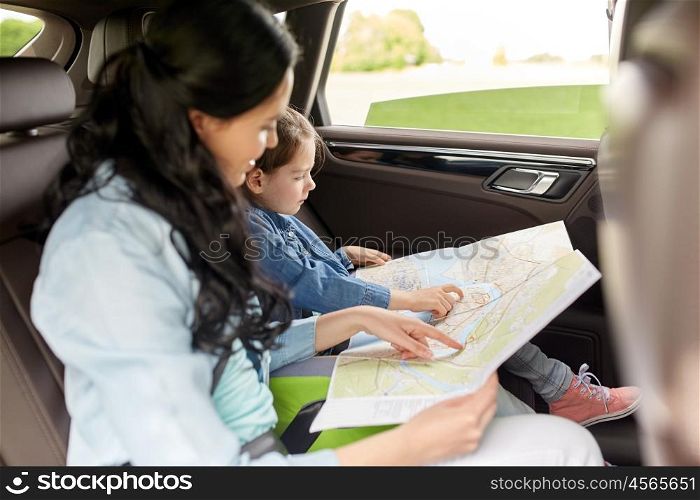 family, transport, road trip and people concept - happy woman and little daughter with map driving in car