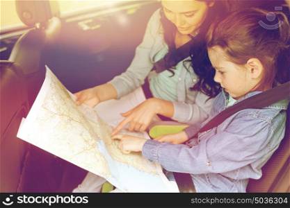 family, transport, road trip and people concept - happy woman and little daughter with map driving in car. happy family with travel map driving in car
