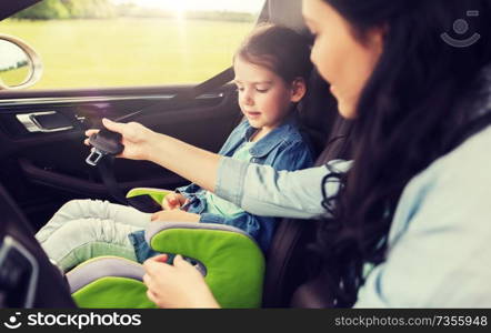 family, transport, road trip and people concept - happy woman fastening child with safety seat belt in car. happy woman fastening child with seat belt in car