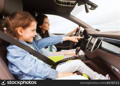 family, transport, road trip and people concept - happy woman with little daughter driving in car