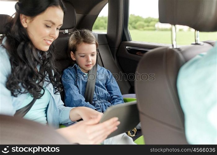 family, transport, road trip, travel and people concept - happy woman and little daughter with tablet pc computer driving in car