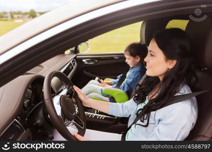 family, transport, road trip, travel and people concept - happy woman and little daughter with smartphone driving in car