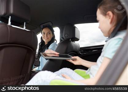 family, transport, road trip, travel and people concept - happy woman giving tablet pc computer to little daughter in car