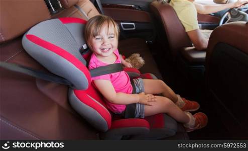family, transport, safety, road trip and people concept - happy little girl sitting in baby car seat and father driving