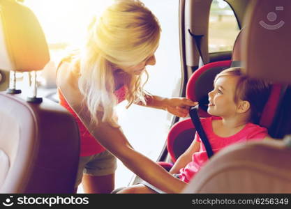 family, transport, safety, road trip and people concept - happy mother fastening child with car seat belt