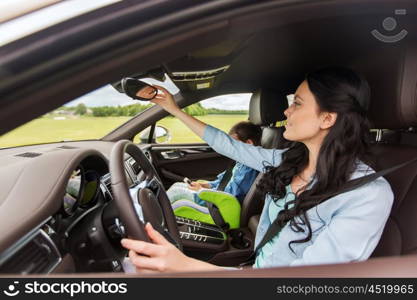 family, transport, safety, road trip and people concept - happy woman with little daughter driving car and looking to rearview mirror