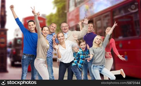 family, travel, tourism and people concept - group of happy men, women and boy having fun and waving hands over london city street background