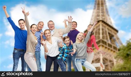 family, travel, tourism and people concept - group of happy men, women and boy having fun and waving hands over eiffel tower background