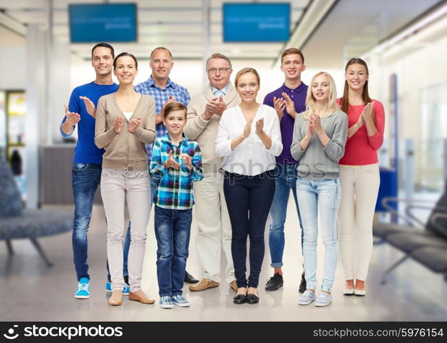 family, travel, tourism and people concept - group of smiling men, women and boy applauding over airport waiting room background