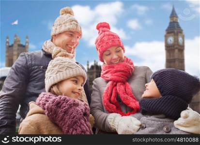 family, travel, tourism, winter holidays and people concept - happy parents with kids over london city background