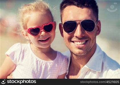 family, travel, vacation, adoption and people concept - happy father with little girl in sunglasses on summer beach