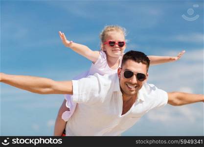 family, travel, vacation, adoption and people concept - happy man and little girl in sunglasses having fun over blue sky background