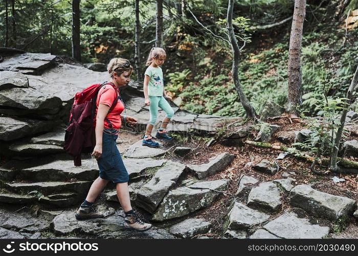 Family trip in mountains. Mother with little girl walking on mountain path, actively spending summer time together. Enjoying the outdoors in the summer trip vacation
