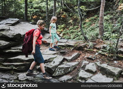 Family trip in mountains. Mother with little girl walking on mountain path, actively spending summer time together. Enjoying the outdoors in the summer trip vacation