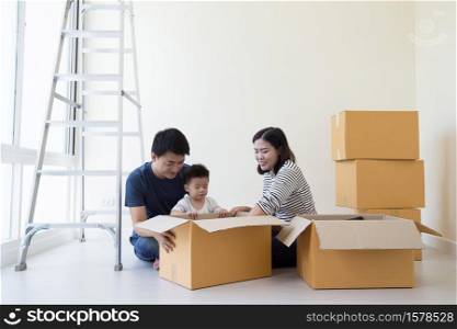 Family unpacking boxes in new home on moving day, Happy father mother and son is having fun with cardboard boxes in the bedroom of new house