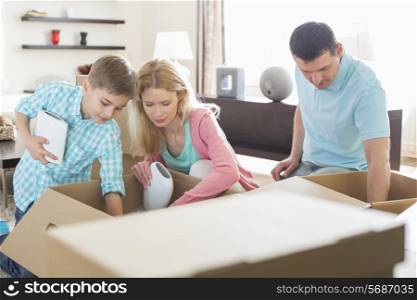 Family unpacking cardboard boxes in new house