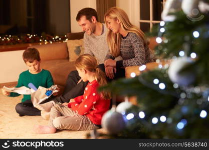 Family Unwrapping Gifts By Christmas Tree