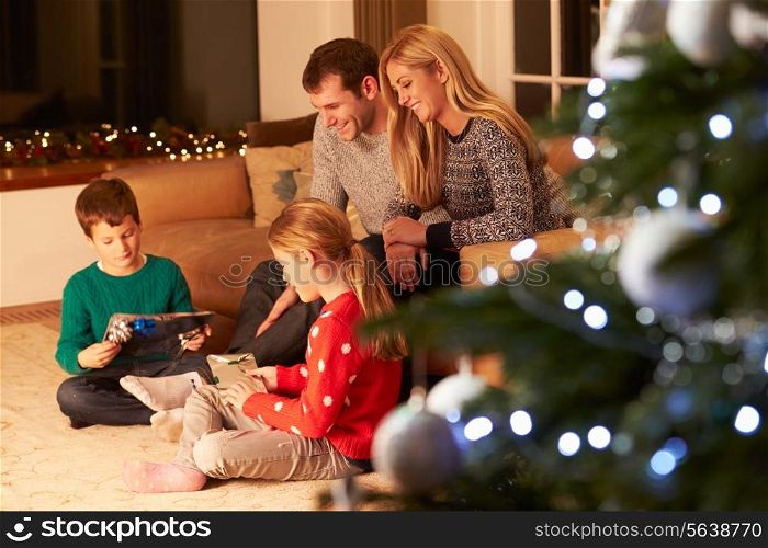 Family Unwrapping Gifts By Christmas Tree