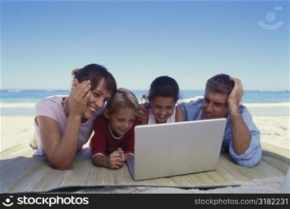 Family using a laptop on the beach