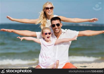 family, vacation, adoption and people concept - happy man, woman and little girl in sunglasses having fun on summer beach