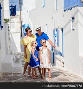 Family vacation in Europe. Parents and kids at street of typical greek traditional village on Mykonos Island, in Greece. Family having fun outdoors on Mykonos streets