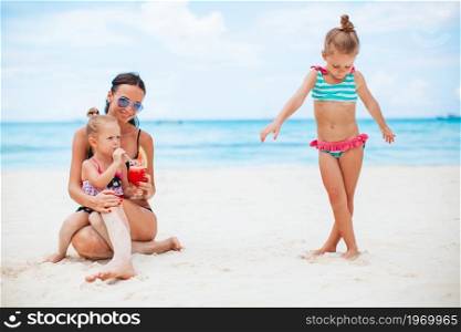 Family vacation. Mother and little girls on vacation on the beach. Adorable little girls and young mother on tropical white beach